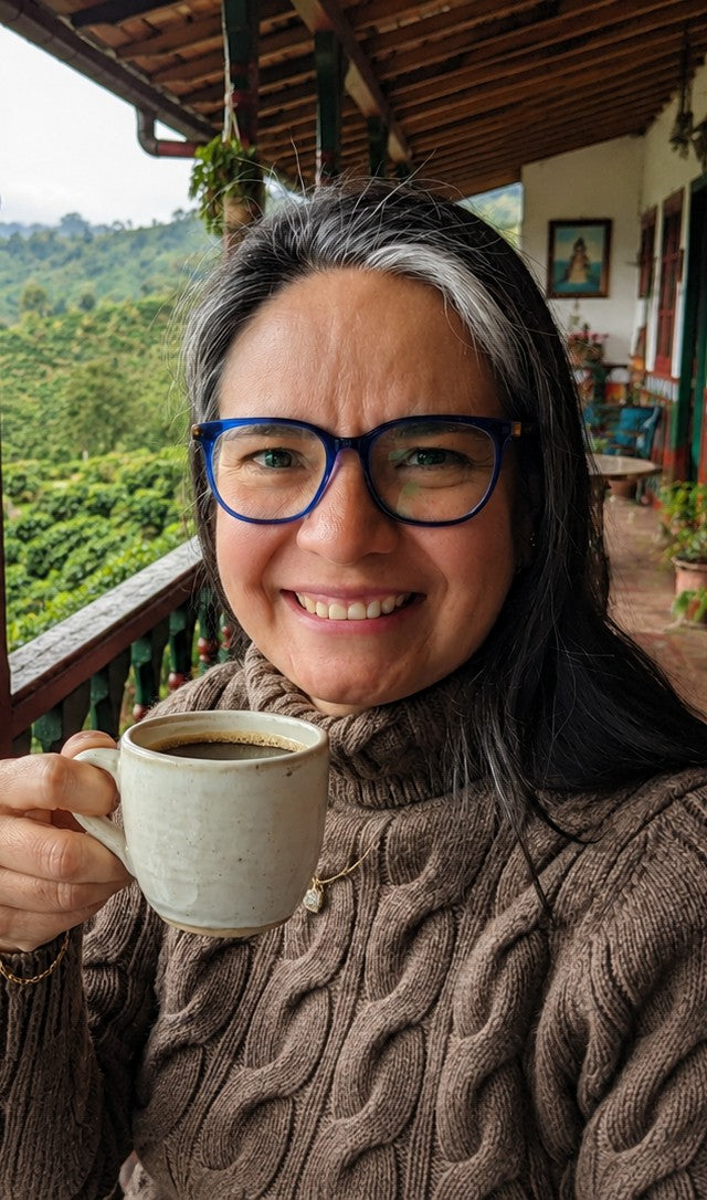 Zulma with a cup of coffee on a farm balcony in Colombia